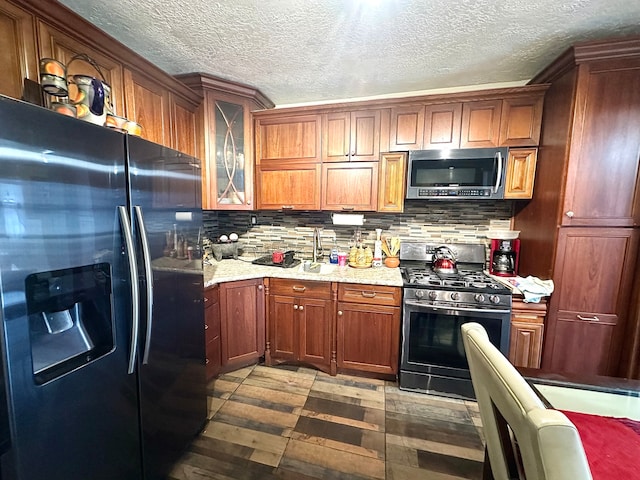 kitchen with light stone countertops, decorative backsplash, stainless steel appliances, and a textured ceiling