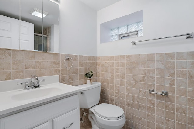 bathroom featuring vanity, toilet, a shower with shower door, and tile walls