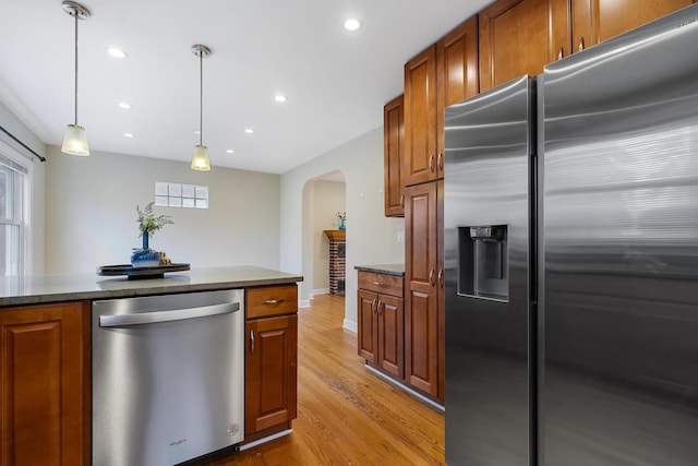 kitchen featuring decorative light fixtures, light hardwood / wood-style floors, and appliances with stainless steel finishes