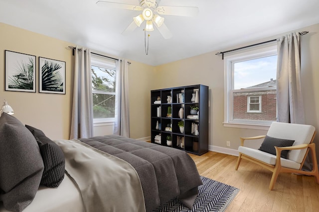 bedroom featuring ceiling fan, light hardwood / wood-style floors, and multiple windows