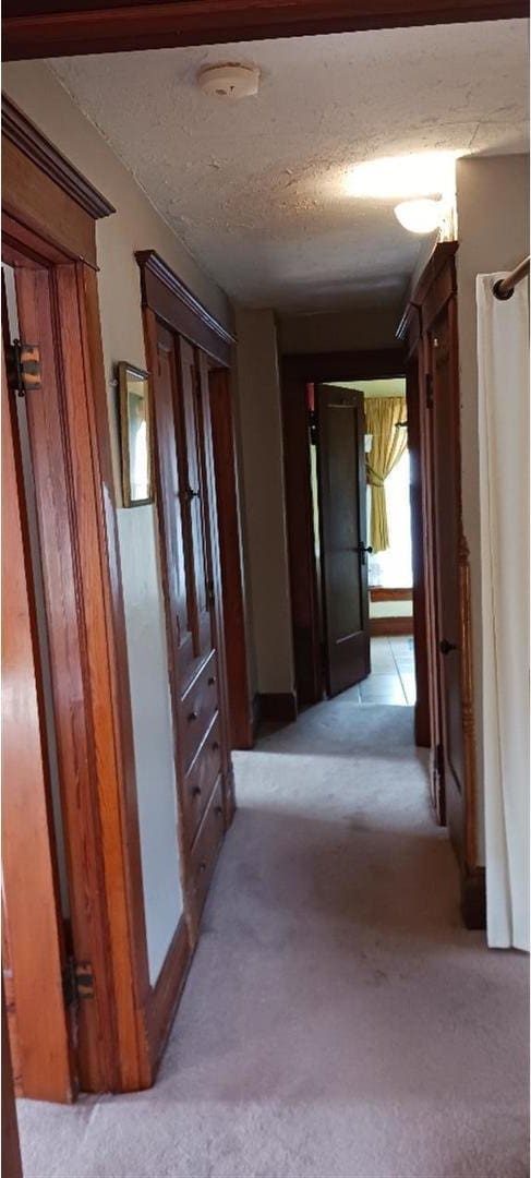 corridor with a textured ceiling and light carpet