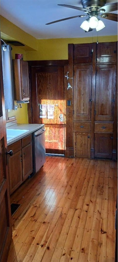 kitchen with light wood-type flooring, dark brown cabinetry, ceiling fan, and dishwasher