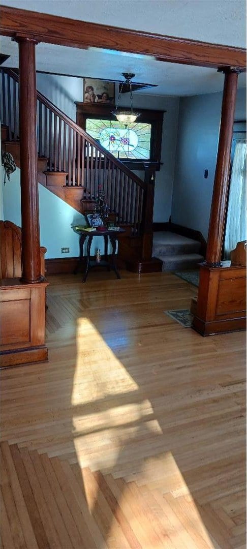 stairway with parquet floors and decorative columns