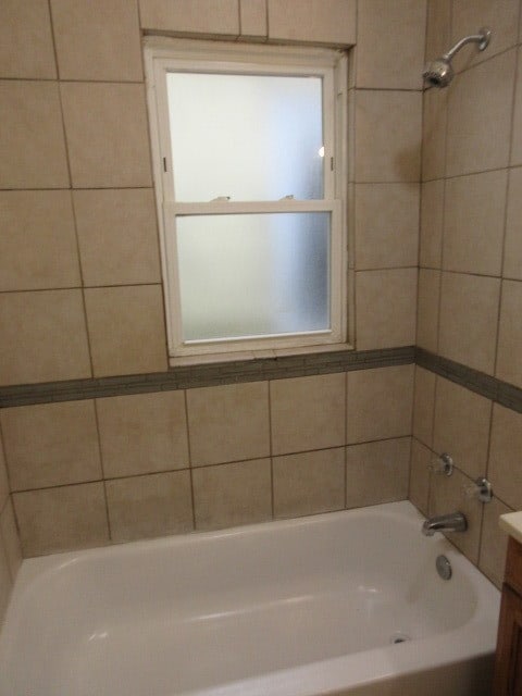 bathroom with vanity, tiled shower / bath combo, and a wealth of natural light