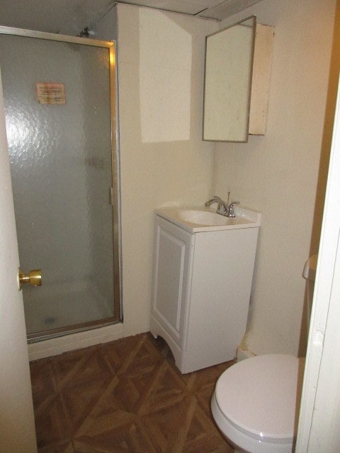 bathroom featuring vanity, toilet, parquet floors, and a shower with shower door