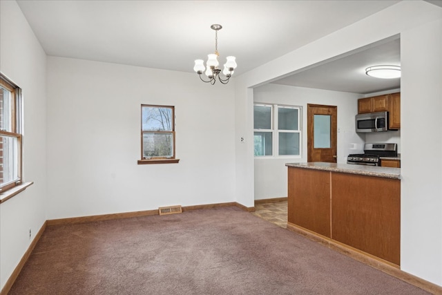 kitchen featuring an inviting chandelier, light colored carpet, pendant lighting, and appliances with stainless steel finishes