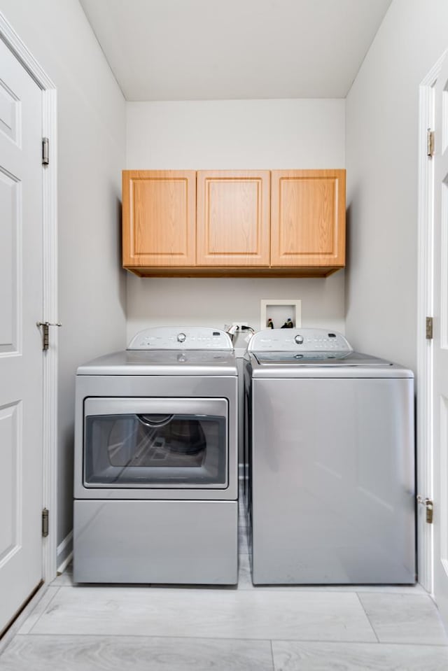 laundry room featuring washer and dryer and cabinets