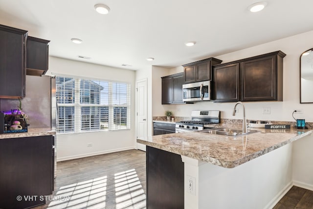 kitchen featuring sink, dark brown cabinets, light hardwood / wood-style floors, kitchen peninsula, and stainless steel appliances