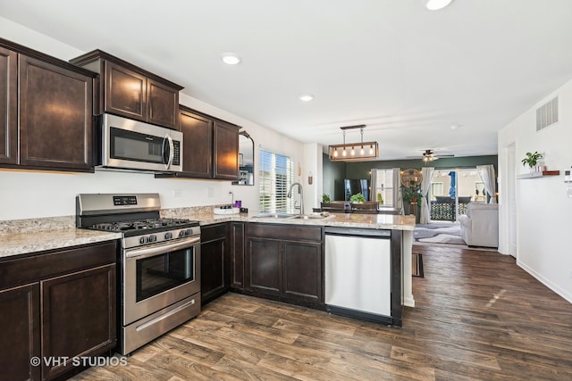 kitchen with kitchen peninsula, sink, stainless steel appliances, and dark hardwood / wood-style floors