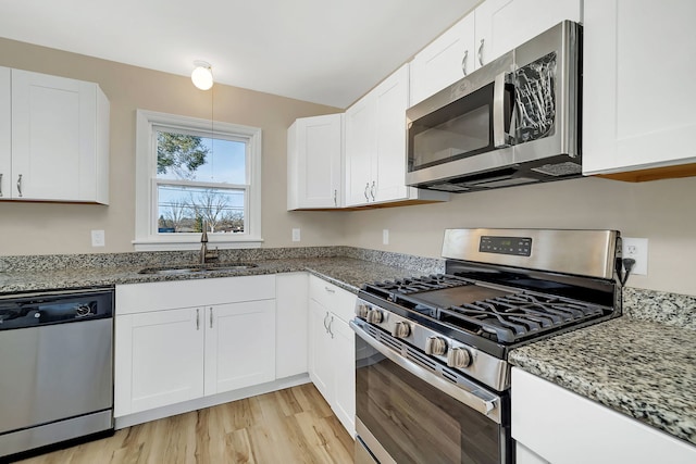 kitchen with light wood-type flooring, white cabinetry, stainless steel appliances, and stone counters