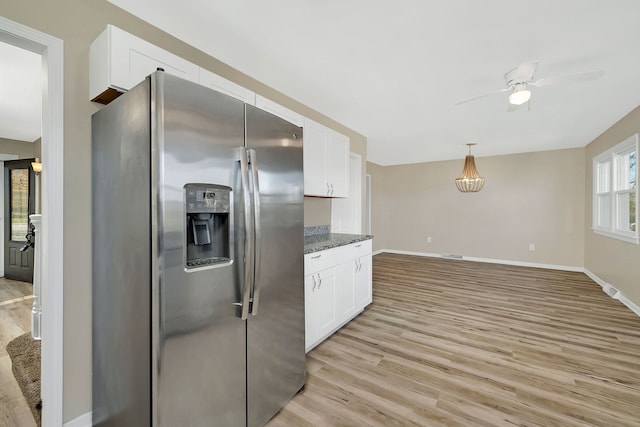 kitchen with white cabinets, stainless steel fridge with ice dispenser, dark stone counters, and light hardwood / wood-style flooring