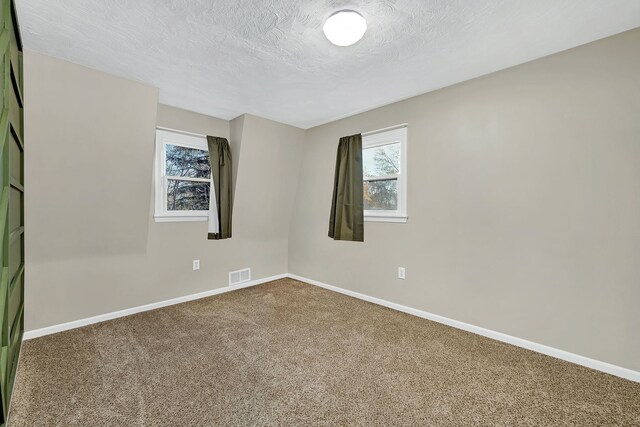 carpeted spare room with a textured ceiling