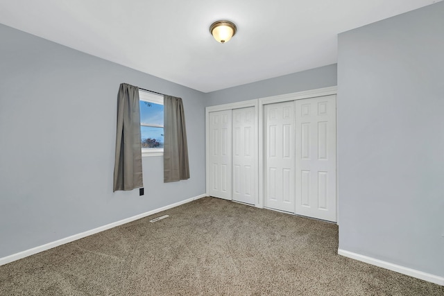 unfurnished bedroom featuring carpet and two closets