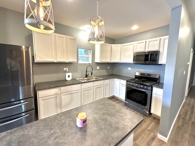 kitchen featuring stainless steel appliances, sink, decorative light fixtures, hardwood / wood-style floors, and white cabinetry