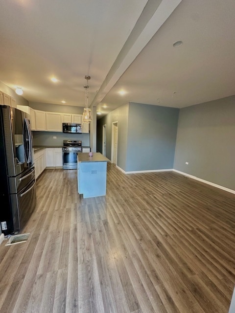 kitchen featuring appliances with stainless steel finishes, a center island, light hardwood / wood-style floors, white cabinetry, and hanging light fixtures