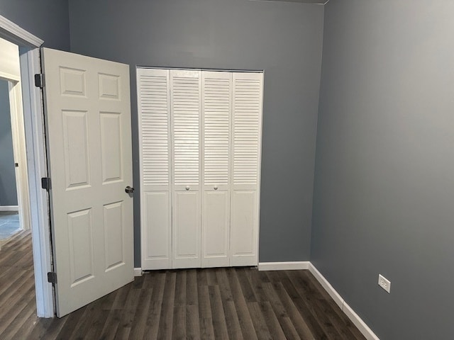 unfurnished bedroom featuring a closet and dark hardwood / wood-style floors