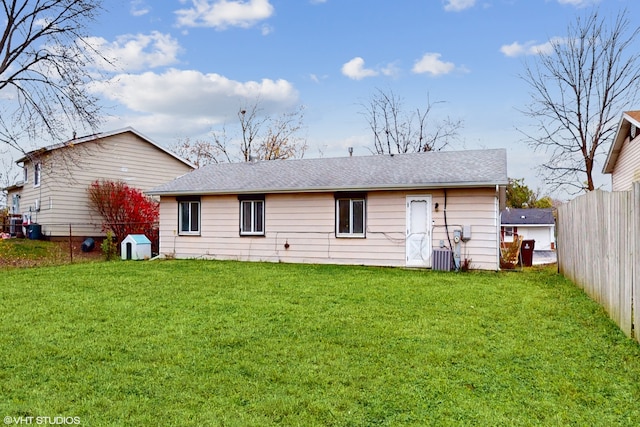 rear view of house with central air condition unit and a yard