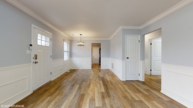 foyer entrance featuring a chandelier, light wood-type flooring, and ornamental molding