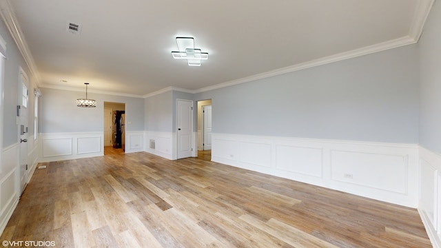 unfurnished room with light hardwood / wood-style floors, an inviting chandelier, and ornamental molding