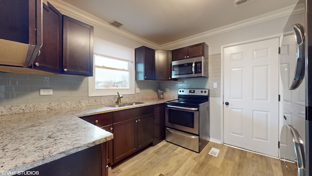 kitchen featuring stacked washer and clothes dryer, sink, appliances with stainless steel finishes, light hardwood / wood-style floors, and light stone counters