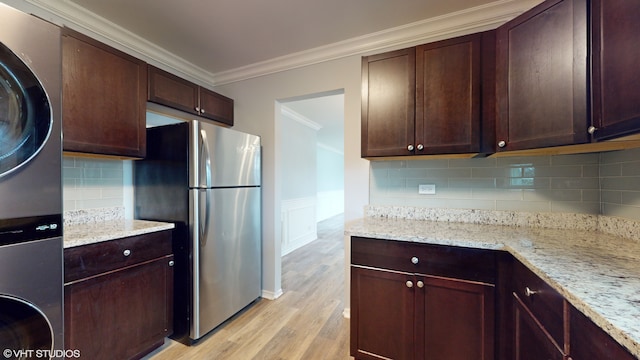 kitchen with crown molding, light hardwood / wood-style flooring, stainless steel fridge, light stone countertops, and tasteful backsplash