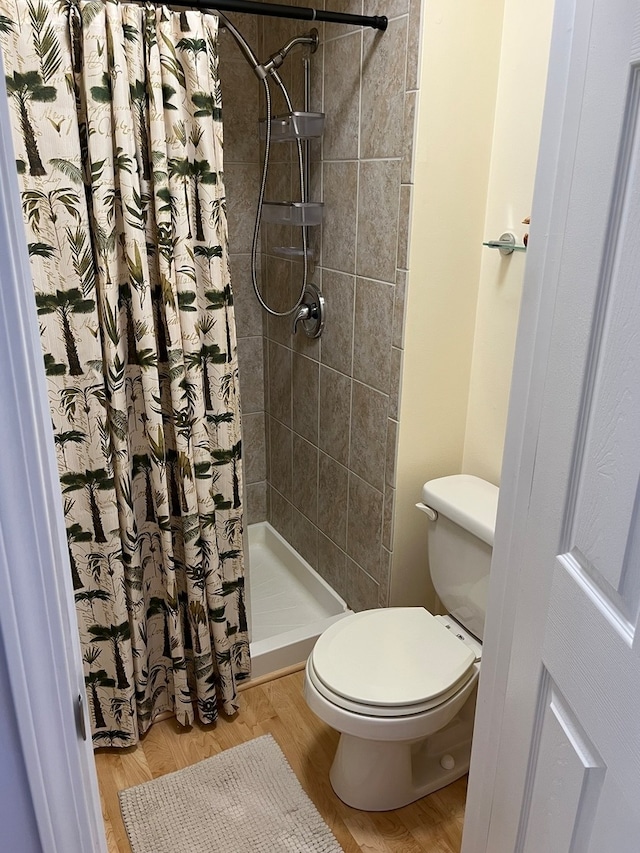 bathroom featuring hardwood / wood-style floors, toilet, and walk in shower