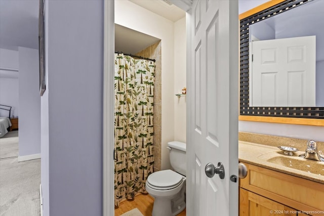 bathroom featuring walk in shower, hardwood / wood-style flooring, vanity, and toilet