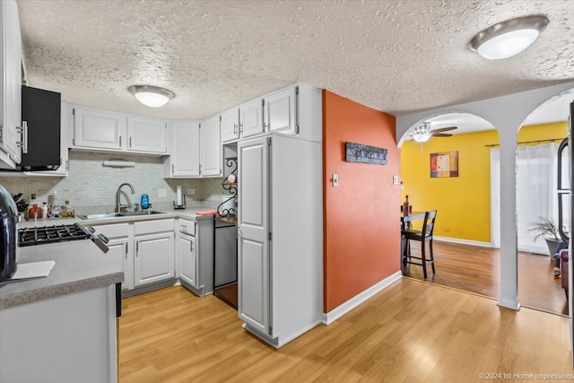 kitchen featuring white cabinets, a textured ceiling, light wood-type flooring, and sink