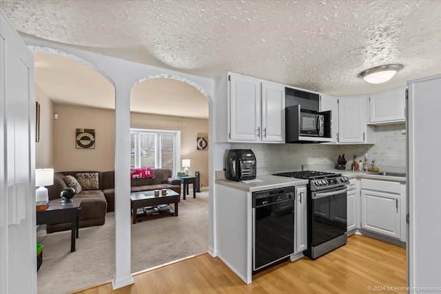 kitchen with white cabinets, light hardwood / wood-style flooring, stainless steel gas stove, black dishwasher, and tasteful backsplash