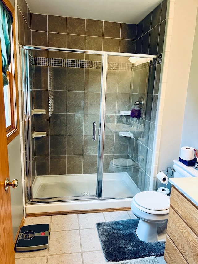 bathroom with tile patterned flooring, vanity, toilet, and a shower with shower door