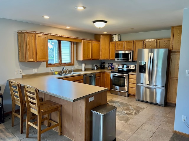 kitchen with a kitchen breakfast bar, kitchen peninsula, sink, and appliances with stainless steel finishes