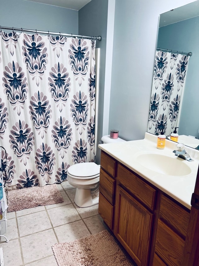 bathroom featuring tile patterned flooring, vanity, toilet, and curtained shower