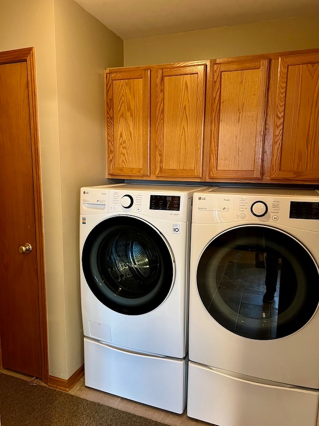 laundry room with light tile patterned floors, cabinets, and independent washer and dryer