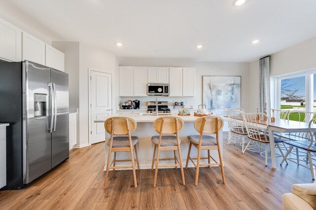 kitchen featuring white cabinets, a kitchen island with sink, sink, and appliances with stainless steel finishes