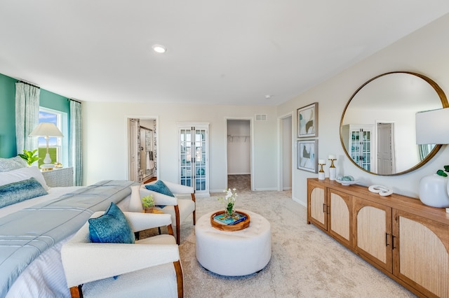 bedroom featuring a walk in closet and light carpet