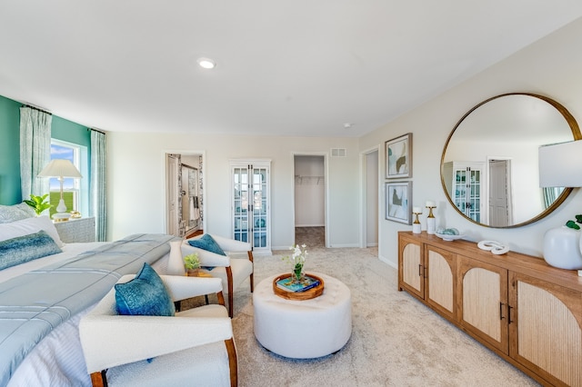bedroom with a walk in closet, light carpet, baseboards, and visible vents