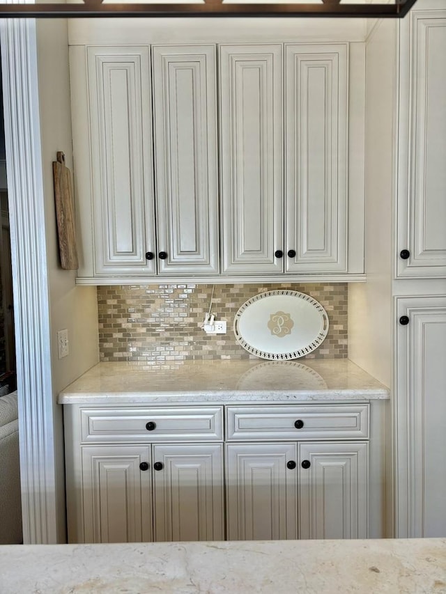 interior space featuring white cabinets, backsplash, and light stone counters