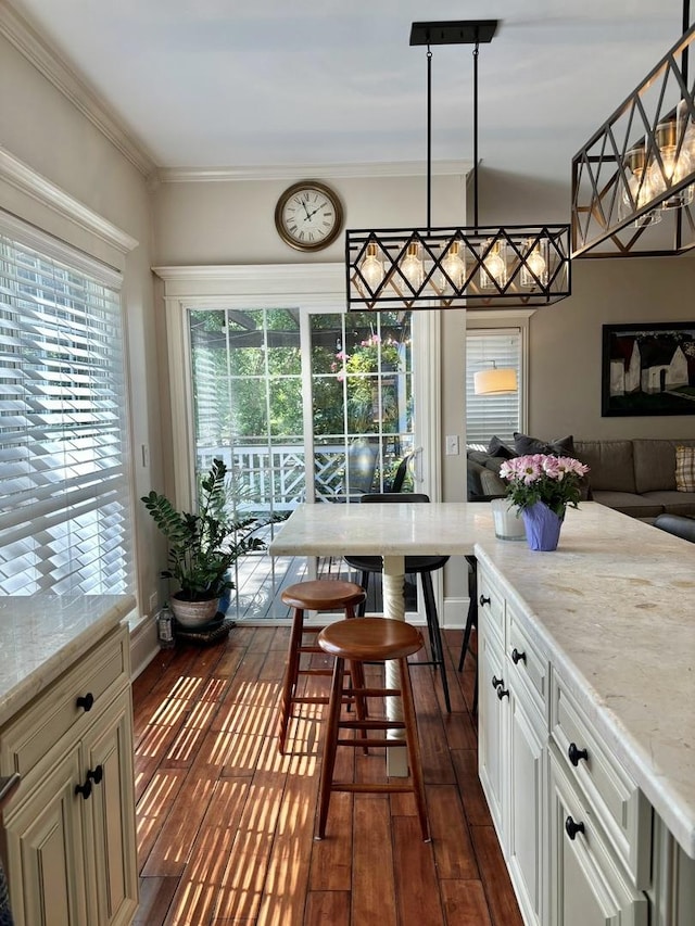 kitchen with pendant lighting, dark hardwood / wood-style flooring, light stone countertops, and crown molding