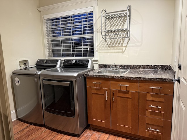 clothes washing area with separate washer and dryer, sink, cabinets, and hardwood / wood-style flooring