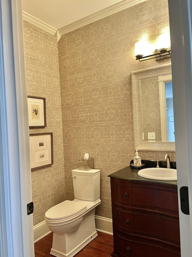 bathroom featuring toilet, hardwood / wood-style floors, vanity, and ornamental molding