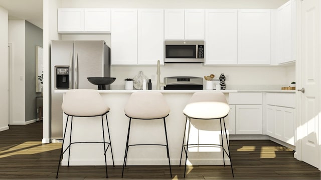 kitchen with a kitchen breakfast bar, stainless steel appliances, white cabinetry, and dark wood-type flooring