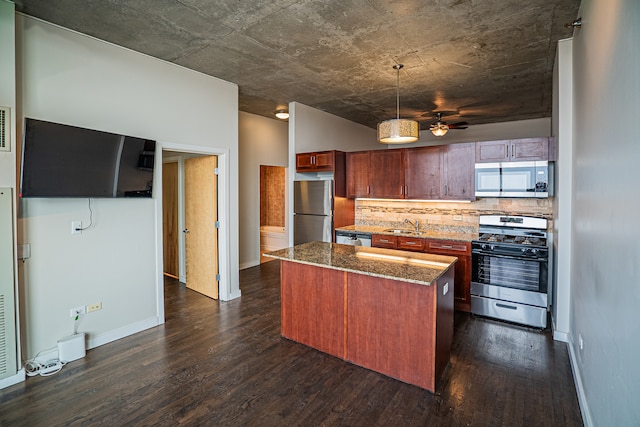 kitchen featuring dark stone countertops, dark hardwood / wood-style flooring, a kitchen island, and appliances with stainless steel finishes