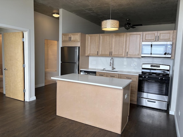 kitchen with stainless steel appliances, light brown cabinetry, a sink, dark wood-type flooring, and light countertops