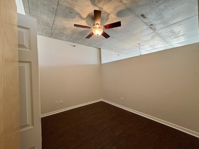 empty room with dark wood-style floors, ceiling fan, and baseboards