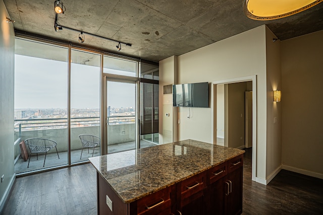 kitchen with dark stone countertops, a kitchen island, a healthy amount of sunlight, and dark hardwood / wood-style floors