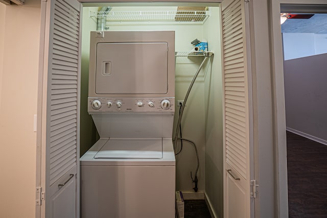 laundry room with dark hardwood / wood-style flooring and stacked washer / drying machine