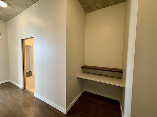 hallway featuring dark wood-style flooring and baseboards