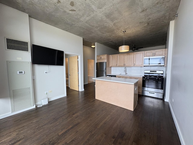 kitchen with gas range, white microwave, freestanding refrigerator, a sink, and dark wood-style floors