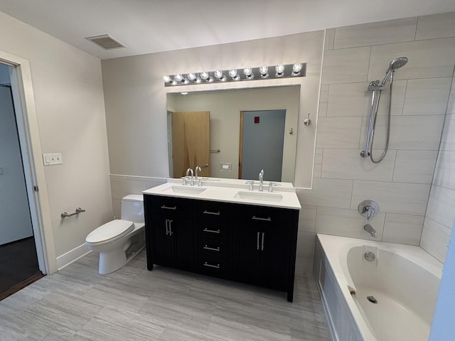 bathroom with double vanity, toilet, and washtub / shower combination