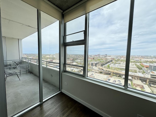 unfurnished room featuring dark wood finished floors, a view of city, and baseboards